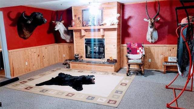 carpeted living area featuring a wainscoted wall, a large fireplace, and wood walls