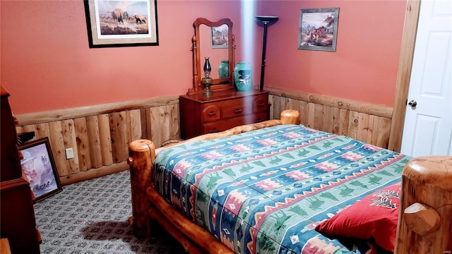 carpeted bedroom with wainscoting and wood walls