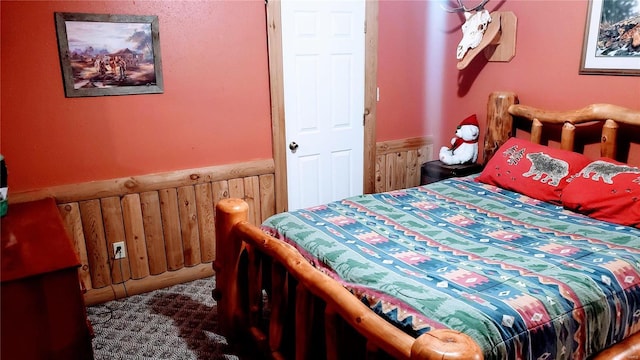 bedroom with wainscoting, wood walls, and carpet