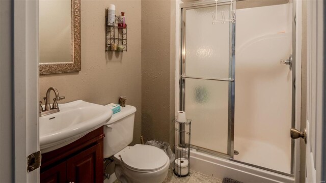 full bath with toilet, a stall shower, vanity, and a textured wall