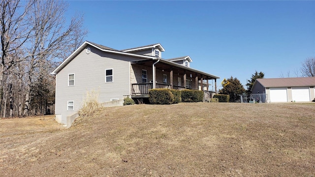 view of side of property featuring a porch, a lawn, and a detached garage