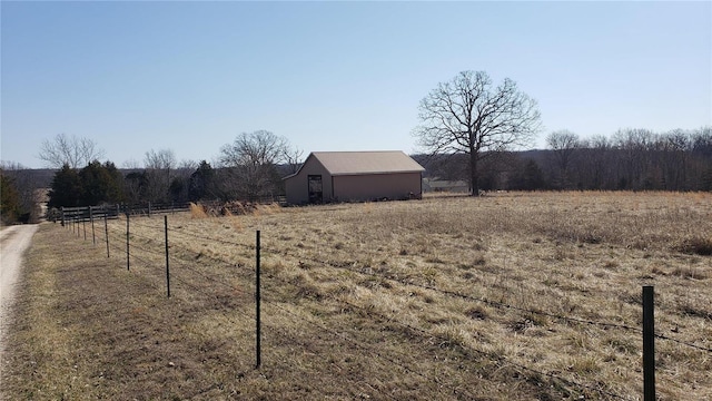 view of yard with an outbuilding, a rural view, a pole building, and fence