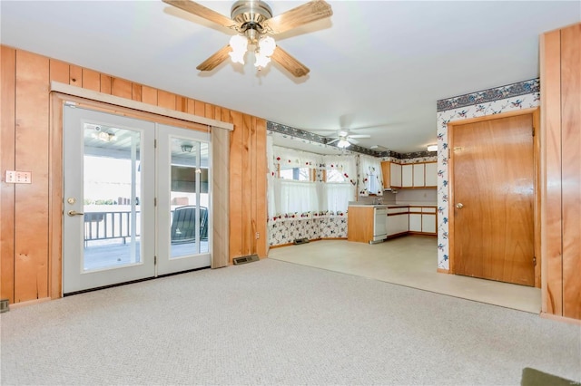 unfurnished living room featuring a wealth of natural light, light carpet, and wood walls