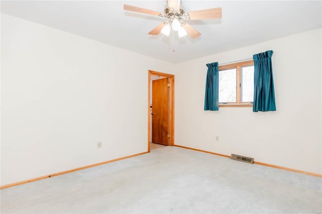 carpeted spare room with a ceiling fan, visible vents, and baseboards