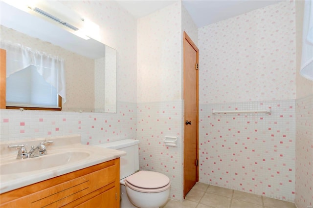 bathroom with wainscoting, toilet, tile patterned floors, vanity, and tile walls