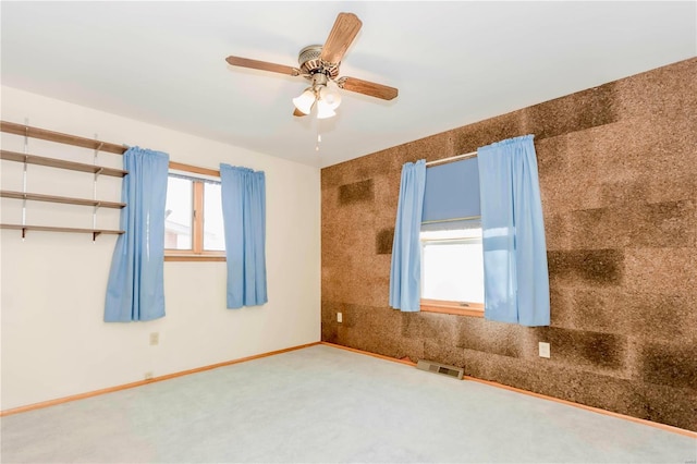 spare room featuring carpet floors, a ceiling fan, visible vents, and baseboards