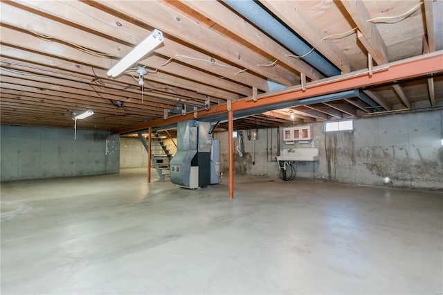 basement with a sink, heating unit, and stairs