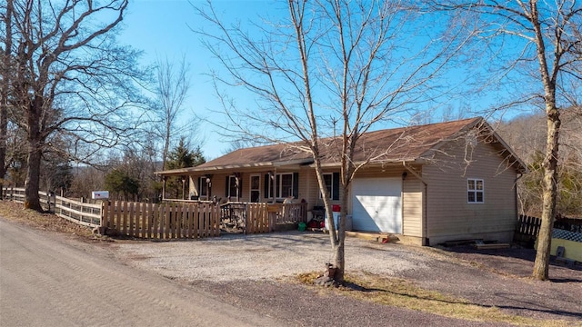 ranch-style house with an attached garage, covered porch, driveway, and fence