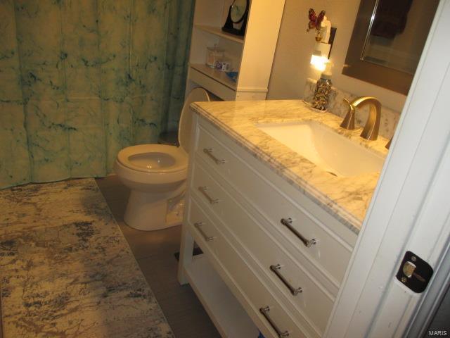 bathroom featuring a shower with shower curtain, vanity, and toilet