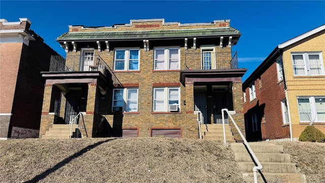 view of front of property with brick siding, cooling unit, and a balcony