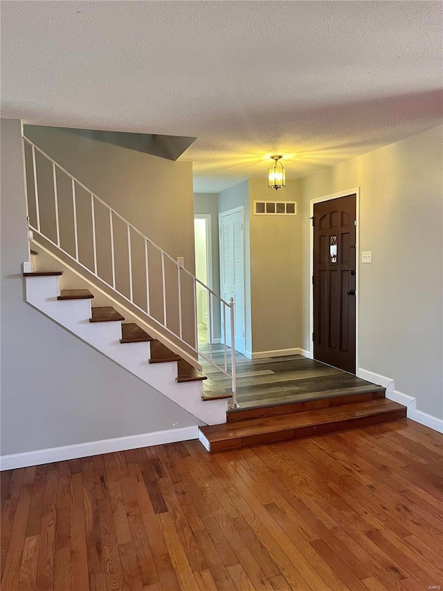 entryway with baseboards, visible vents, stairway, hardwood / wood-style floors, and a textured ceiling