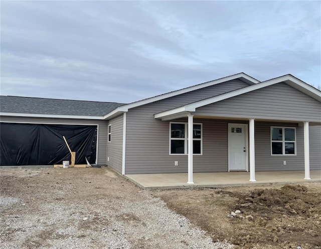 view of front of home with driveway, a porch, roof with shingles, and an attached garage