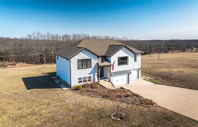 view of front of property with concrete driveway, an attached garage, board and batten siding, a front yard, and stone siding