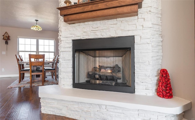 interior details with a stone fireplace, wood finished floors, and baseboards