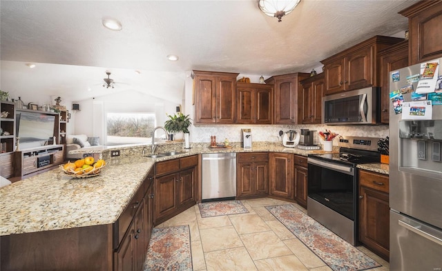 kitchen with stainless steel appliances, a peninsula, a sink, vaulted ceiling, and decorative backsplash