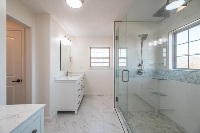 full bath with marble finish floor, a stall shower, vanity, and baseboards