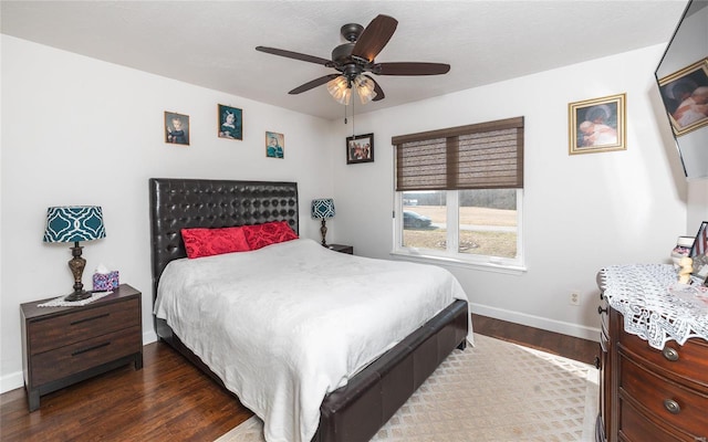 bedroom with ceiling fan, baseboards, and dark wood-style flooring