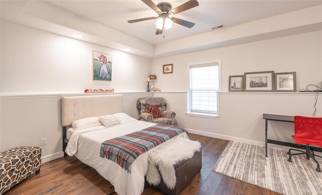 bedroom featuring a ceiling fan, wood finished floors, visible vents, and baseboards