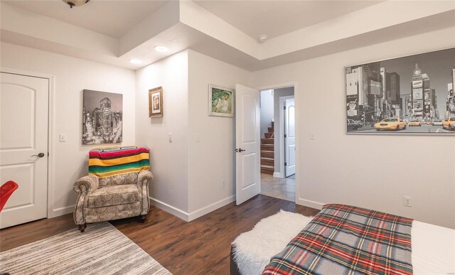 bedroom with a tray ceiling, baseboards, and wood finished floors