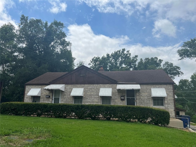 view of front of home featuring a chimney, a front lawn, and roof with shingles