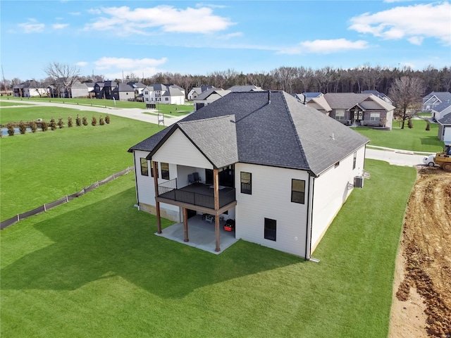 rear view of house with a residential view, roof with shingles, a deck, a yard, and a patio area