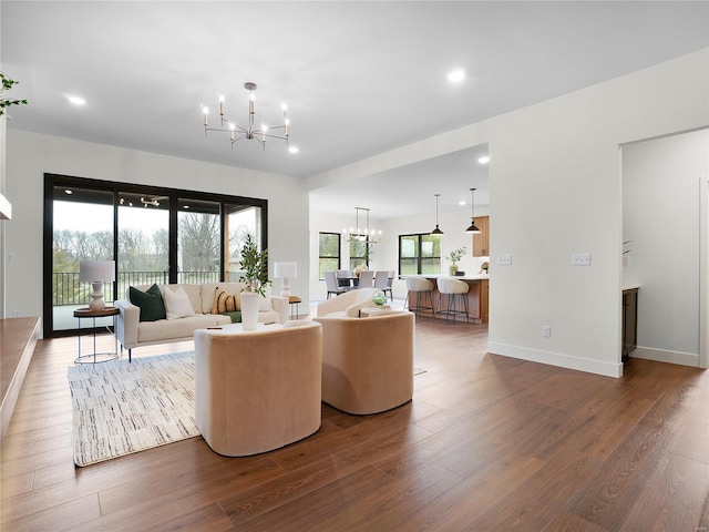 living room featuring an inviting chandelier, baseboards, dark wood finished floors, and recessed lighting