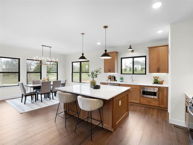 kitchen with a kitchen island, dark wood-type flooring, a sink, and light countertops