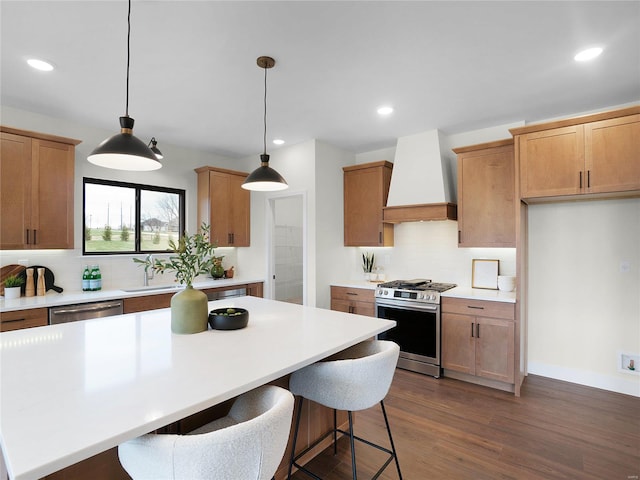 kitchen with tasteful backsplash, dark wood-style floors, appliances with stainless steel finishes, light countertops, and premium range hood