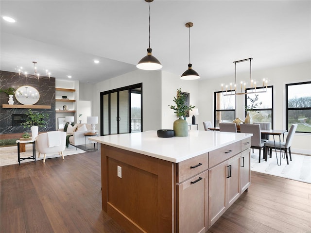 kitchen with dark wood-type flooring, a high end fireplace, open floor plan, light countertops, and a center island