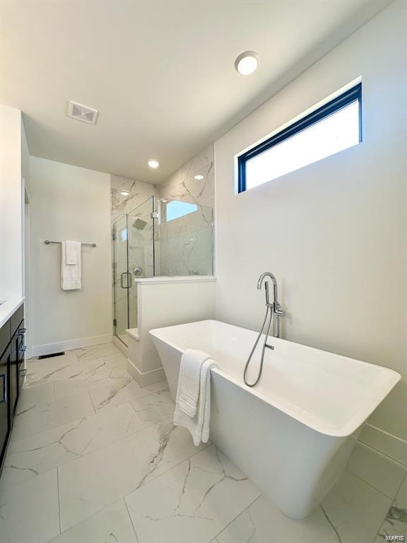 bathroom with marble finish floor, a soaking tub, visible vents, a stall shower, and baseboards