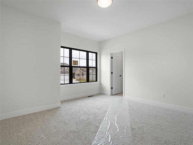 unfurnished room featuring baseboards, visible vents, and light colored carpet