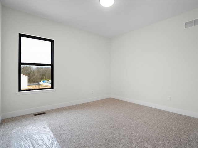 empty room featuring carpet, visible vents, and baseboards
