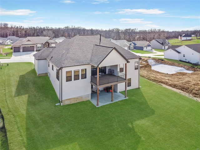 back of property with a patio area, a residential view, a lawn, and roof with shingles