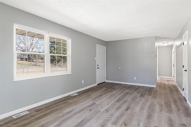 spare room with visible vents, baseboards, and wood finished floors