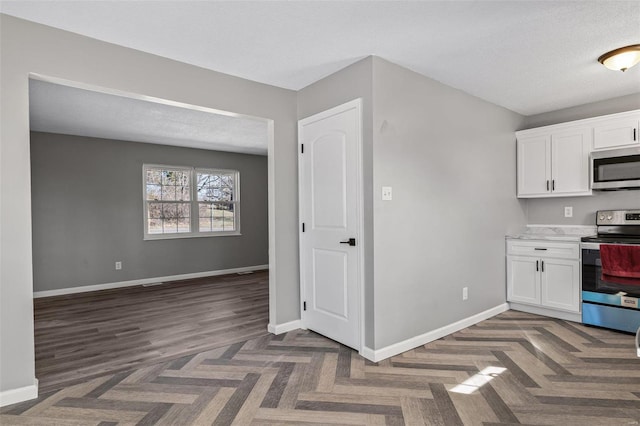 kitchen featuring baseboards, stainless steel appliances, and white cabinets