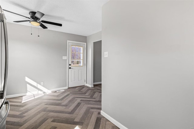 foyer entrance with a textured ceiling, a ceiling fan, and baseboards