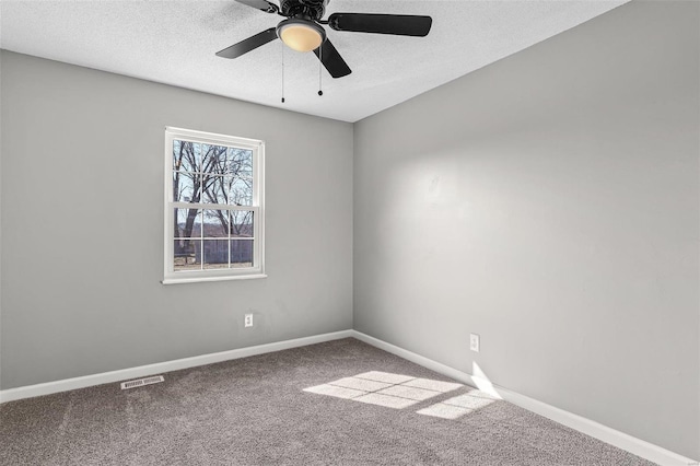 empty room with carpet floors, visible vents, a textured ceiling, and baseboards