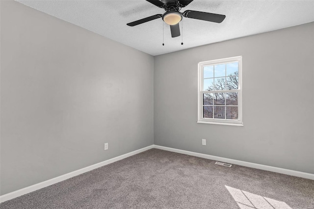 carpeted empty room featuring a textured ceiling, ceiling fan, visible vents, and baseboards