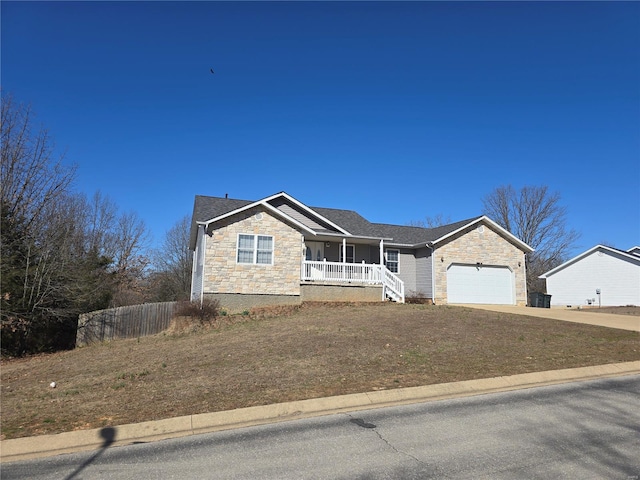 ranch-style house with fence, concrete driveway, covered porch, a garage, and stone siding