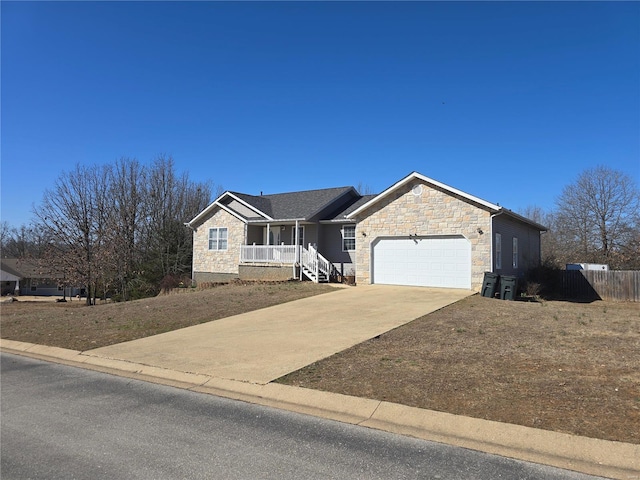 ranch-style home featuring stone siding, fence, covered porch, concrete driveway, and an attached garage