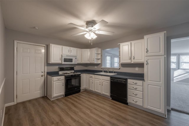 kitchen featuring range with gas cooktop, dark countertops, white microwave, a sink, and dishwasher