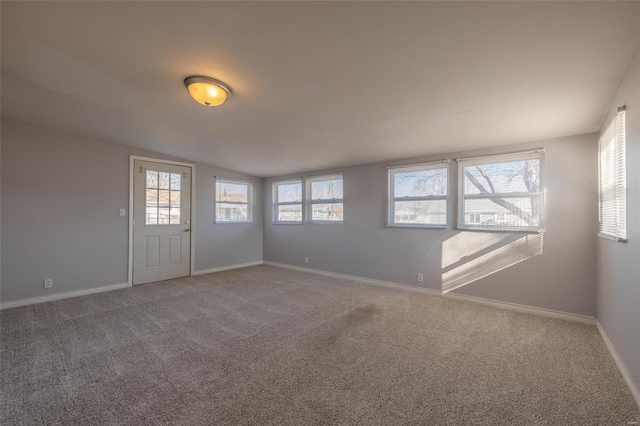 carpeted spare room featuring vaulted ceiling and baseboards