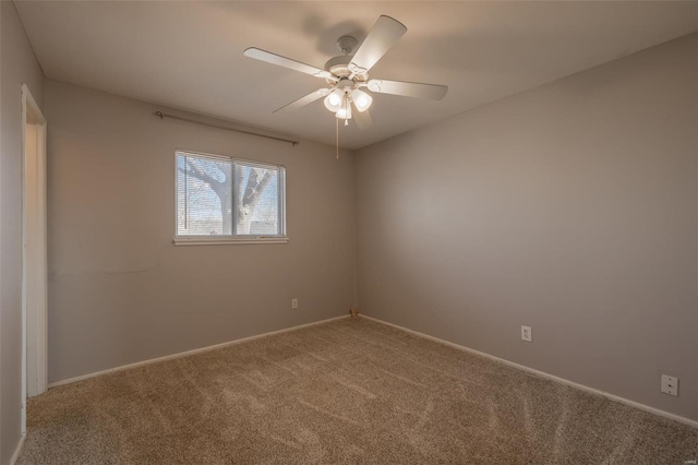 carpeted empty room with ceiling fan and baseboards