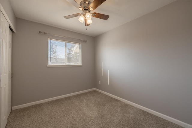 carpeted spare room featuring baseboards and a ceiling fan