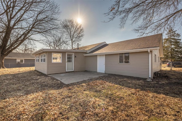 rear view of property with roof with shingles, fence, and a patio