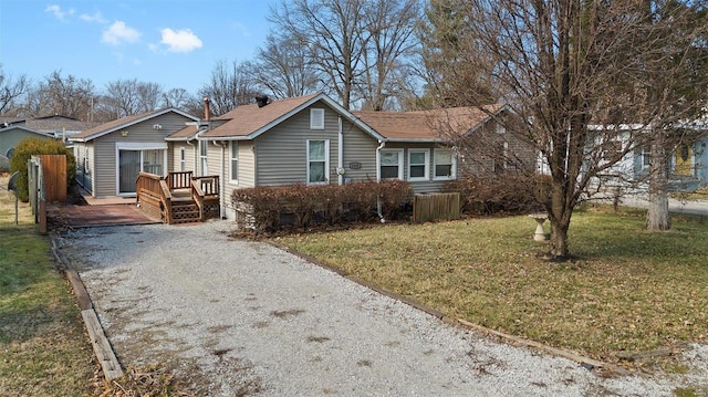 ranch-style house featuring a front yard, fence, driveway, and a wooden deck