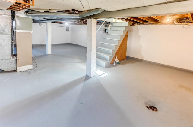 unfinished basement featuring stairway and baseboards