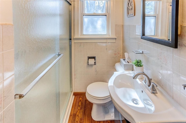 bathroom with toilet, a shower stall, a sink, and wood finished floors