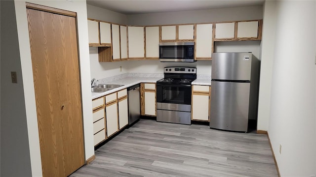 kitchen with stainless steel appliances, light wood-style flooring, a sink, and light countertops