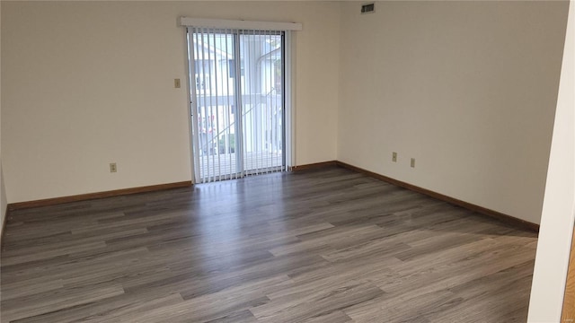 spare room featuring visible vents, baseboards, and wood finished floors